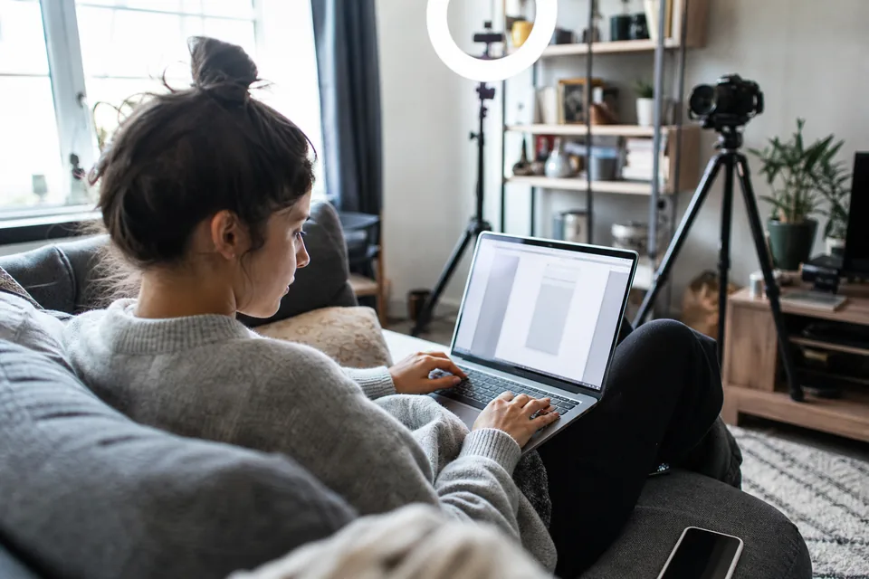 Course creator checking her course sales page on a laptop in her home studio